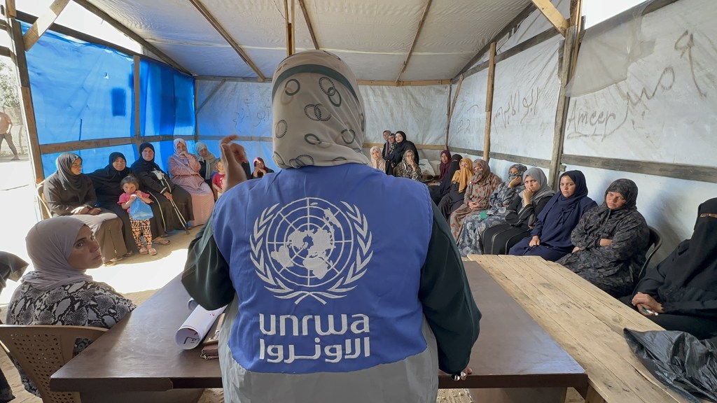 Médico de la división de Salud Medioambiental de UNRWA explicando a las madres desplazadas cómo tratar las picaduras de insectos que afectan a sus hijos.